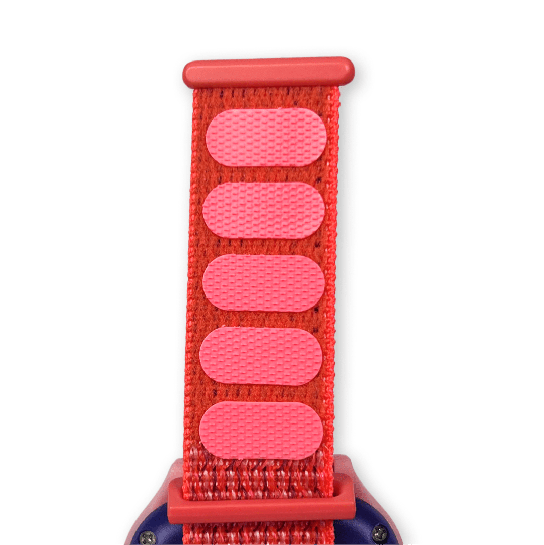 Červený textilní řemínek s růžovými suchými zipy pro snadné nastavení délky, připevněný k chytrým hodinkám.